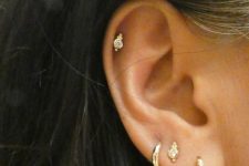bold and chic ear styling with a stacked lobe piercign and a helix one done with shiny gold hoops and studs is a cool idea