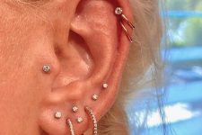 bold and glam ear styling with multiple lobe piercings, a helix and a tragus one done with rhinestone studs and hoops