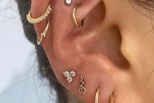 bold ear styling with multiple lobe and a double helix piercing plus a rook and a flat piercing all done with gold hoops and studs