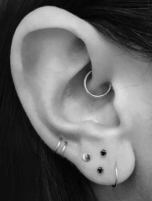 bold modern ear styling with a stacked lobe and a daith piercing done with hoops and studs is a cool idea for an up-to-date look