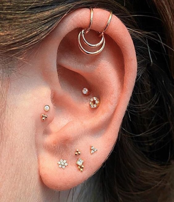 cute ear styling with a stacked lobe, a double tragus, a double onch and a double helix piercing with studs and hoops