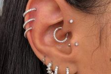 glam ear styling with stacked lobe and helix and flat piercings, a tragus, a forward helix and a daith piercing