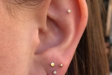 minimalist ear styling with a stacked lobe piercing and a flat one all done with tiny gold studs and a gold hoop earring