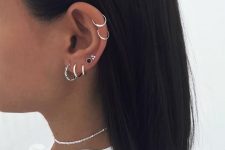 modern ear styling with multiple lobe and a double helix piercing done with chic hoops and studs is wow