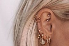 multiple stacked lobe piercings, a double helix piercing and a rook one done with chic gold earrings