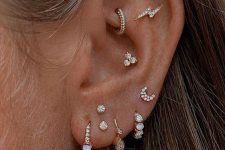 refined ear styling with a stacked lobe, a conch and flat and rook piercing with lots of rhinestone hoops, earrings and studs