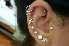 stacked lobe and helix piercings done with stud and hoop earrings plus a tragus and a rook piercing