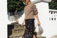 20 a lovely feminine fall outfit with a tan oversized sweater, a black floral midi skirt, black cowboy boots and an embellished bag