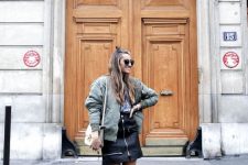 29 a casual fall look with a printed tee, a black zip mini skirt, an olive green bomber jacket, gold boots and a white bag