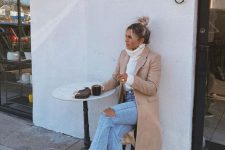 36 a white turtleneck sweater, blue ripped jeans, creamy combat boots, a tan coat and a small bag
