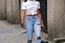With white labeled t-shirt, black chain strap bag and high heels