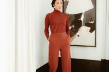 a beautiful monochromatic work look with a ribbed red turtleneck, cropped trousers, burgundy boots, a necklace and statement earrings