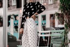 a black and white look with a cutout polka dot top and white polka dot trousers, white shoes and a black bag