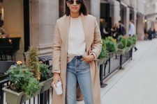 a casual fall look with a white jumper, a tan coat, blue jeans, brown booties is great for work, too