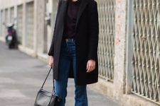 a classy and simple fall look with a black top, blue flare jeans, a black coat and a bag is a stylish solution