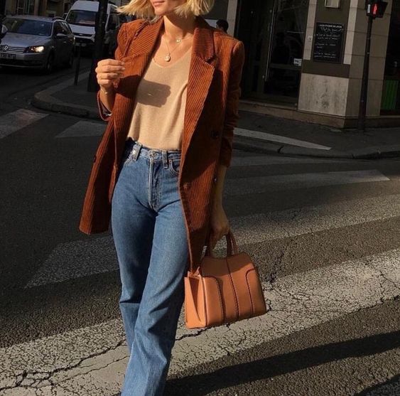 a comfy fall outfit with a neutral top, blue jeans, a tan bag, a rust-colored corduroy oversized blazer is amazing