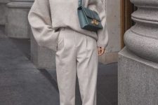a comfy grey outfit with an oversized sweater, trousers, sneakers and a green bag for a color accent