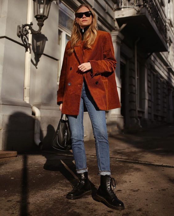 a fall look with a black turtleneck, blue jeans, a rust-colored oversized corduroy blazer, black boots and a black bag