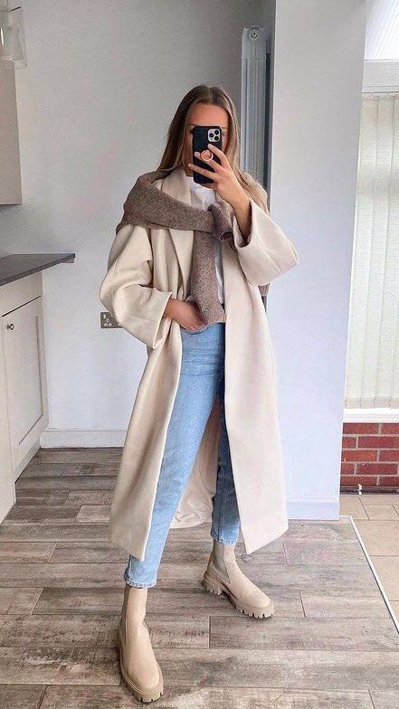 a lovely fall outfit with a white tee, blue cropped jeans, tan Chelsea boots, a tan trench and a jumper over it