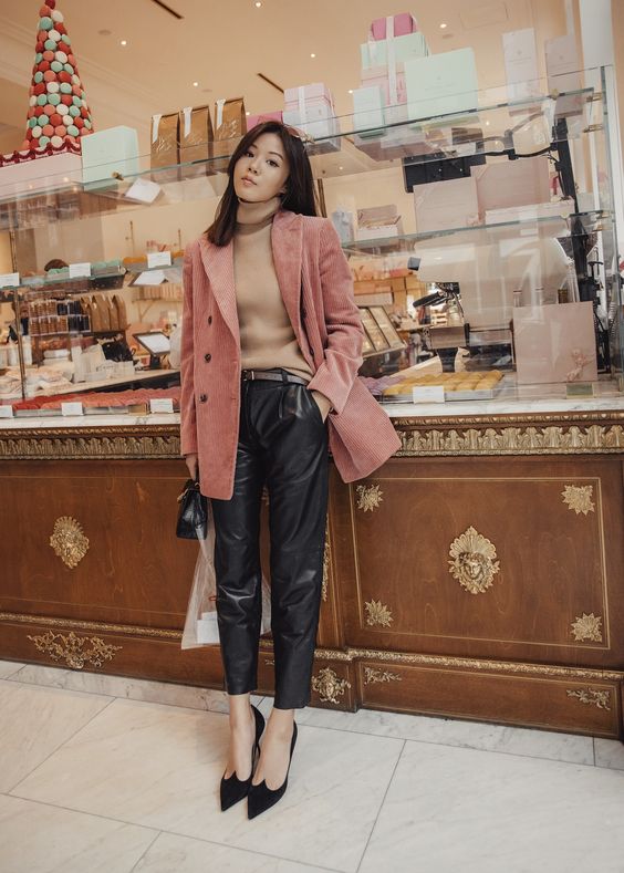 a lovely feminine look with a tan turtleneck, black leather trousers, black heels, a pink corduroy blazer and a black bag