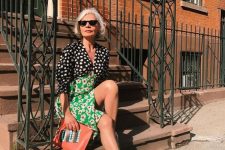 a mix print midi dress showing two different parts – a black and white spot one and a bold green floral one, neutral trainers and a coral clutch