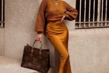 a mustard-colored sweater, a matching slip skirt, black trainers, a brown printed tote and layered necklaces