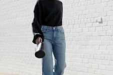 a refined fall outfit with a black bell sleeve blouse, blue jeans, black shoes and a small bucket bag