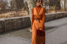 a refined look with a rust-colored turtleneck, an orange slip maxi dress, brown boots, a burgundy bag and a necklace