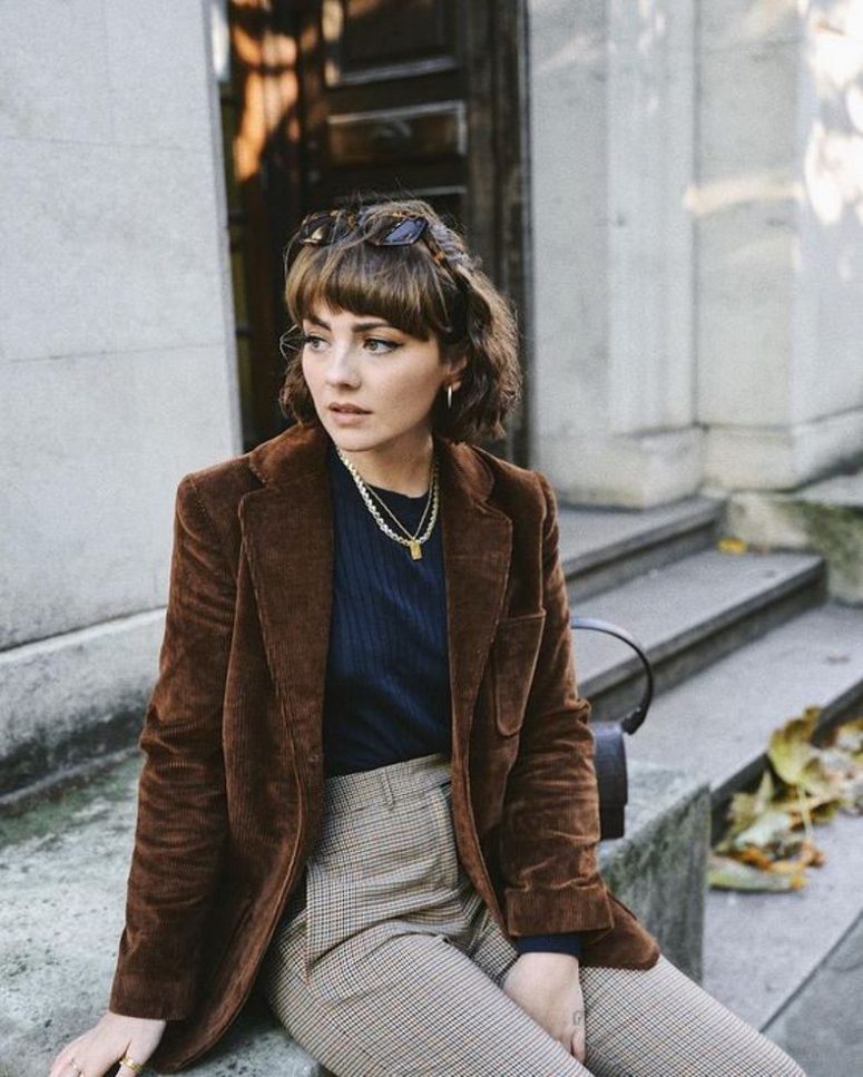 a retro-inspired Parisian look with a navy top, plaid trousers, a brown corduroy blazer, layered necklaces and statement earrings