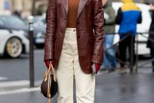 a rust-colored turtleneck, a burgundy leather oversized blazer, white jeans, white booties and a brown bag