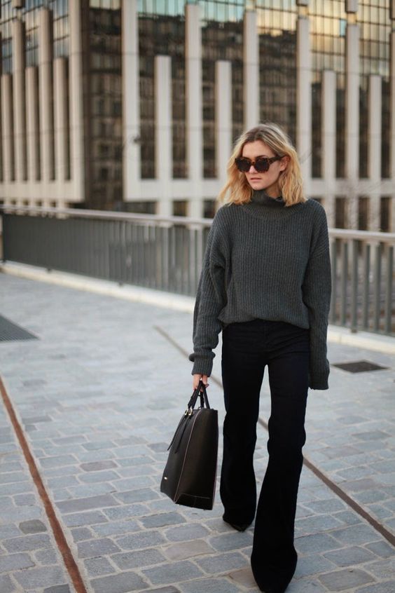 a simple work outfit with a black chunky knit sweater, black flare jeans and boots and a black tote