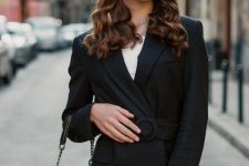 a super chic and classic look with a black pantsuit with a belt, a black bag, a black bucket bag and statement necklaces and earrings