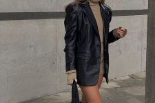 a tan turtleneck and a mini skirt, a black leather blazer, rider boots and a black bag for this fall