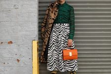 a total zebra print look with a green shirt, a midi white skirt, yellow boots, and faux fur coat and an orange bag