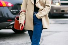 a very simple fall outfit with a black turtleneck, a tan refined blzer, bold blue jeans, black boots and a red bucket bag
