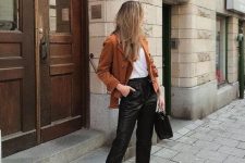 a white t-shirt, black leather trousers, white booties, a black bag, a rust-colored cropped coat for work