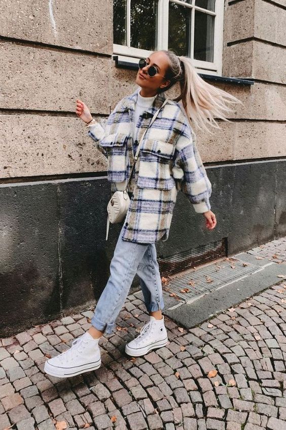 a white turtleneck, blue jeans, a plaid shirt coat, white sneakers and a small white bag