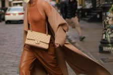 an edgy look with a rust-colored vest, leather trousers, tan heels, a tan bag and a tan coat is very refined