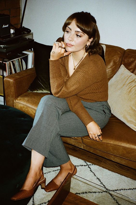 an elegant French chic look with a rust-colored V-neck jumper, grey cropped trousers, rust-colored crocodile leather slingbacks