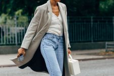 blue barrel jeans, black boots, a white cardigan as a shirt, a grey midi coat and a white suitcase-style bag