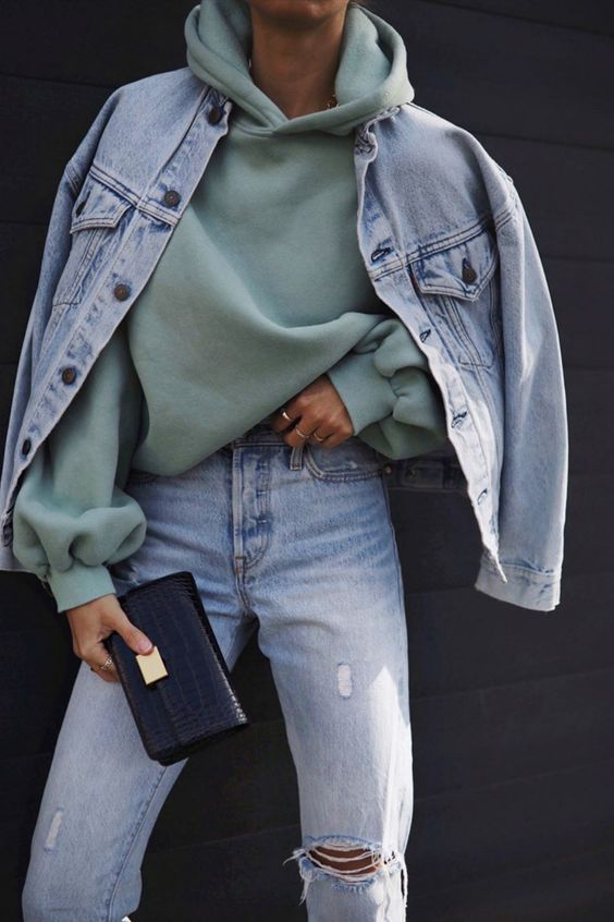 a light green hoodie, blue ripped jeans, a blue denim jacket and a black clutch that you can switch to a comfy tote