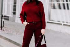 16 a monochromatic burgundy outfit with trousers, a sweater, high heels, a bag, a hat and earrings plus a matching lipstick