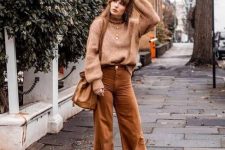 17 a 70s inspired fall outfit with a tan sweater, beige corduroy pants, matching boots, a tan bucket bag and layered necklaces