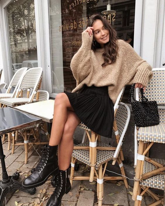 a tan oversized sweater, a black pleated mini skirt, black boots and an embellished black bag for a lovely and girlish look