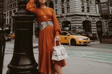 23 a rust-colored A-line midi dress with long sleeves, a snakeskin print belt, a white bag and black lacquer boots for the fall