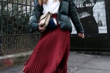 26 a white t-shirt, a burgundy pleated midi skirt, a green puffer jacket and white sneakers plus a creamy bag