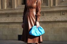 27 a pretty feminine outfit with a brown leather A-line dress with long sleeves and a high neckline, matching tall boots and a bold blut clutch