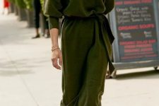 32 a green turtleneck sweater midi dress with a sash, snakeskin print boots, a black leather beret and statement earrings