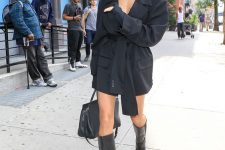 Hailey Bieber wearing a black blazer dress, black knee boots, a black bag for a chic and bold fall look