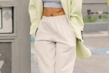 Hailey Bieber wearing a grey crop top, creamy sweatpants, neon green boots and a matching oversized blazer